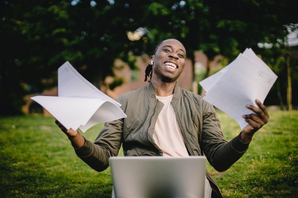 Man with a laptop and some papers smiling
